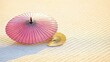 © Somphong - Traditional crimson parasol leaning against golden fan resting on textured tatami floor in soft light
