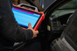 © Aimur - A Car diagnostic specialist using an electronic tablet scanner in an automotive repair garage. Mechanic performing vehicle computer system analysis with professional diagnostic equipment