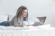 © Cavan Images - Woman communicating at computer, laptop in white bed.
