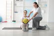 © New Africa - Doctor and patient exercising with medicine ball in clinic