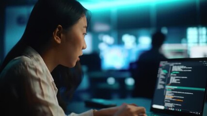 Asian female programmer coding cybersecurity protocols on a laptop screen