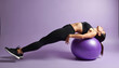 © Maryna - Young woman fitness exercise with purple swiss ball. Female works core muscles, stretches back on purple background. Healthy lifestyle, wellness, flexibility, balance, body strength, yoga, pilates.