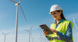 © Inspire Shots Hub - Woman engineer using tablet, wind turbines background, showcasing renewable energy concept