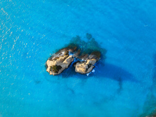 Wall Mural - rocks in the middle of the sea. clear blue water and waves. marine natural landscape. summer seascap