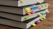 © NN AI - Stack of books with colorful sticky notes bookmarks on wooden surface. Educational study materials with organization tabs for learning and research concept
