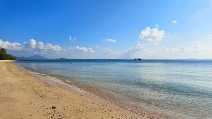 Wall Mural - Calm beach meets clear blue sea, with distant ships and mountains on a sunny day