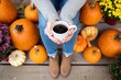 © TeeBundle - Woman holding coffee surrounded by pumpkins on porch enjoying autumn season and fall colors
