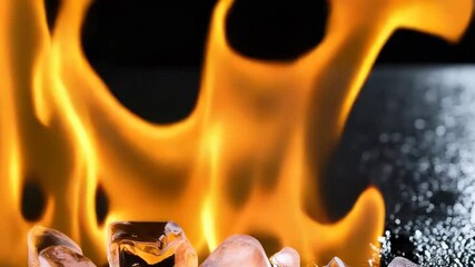 Wall Mural - Close-up view of vibrant orange flames flickering above scattered decorative glass rocks, creating a warm and inviting ambiance on dark base.