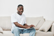 © SHOTPRIME STUDIO - Excited young Black man enjoying work on a laptop at home, wearing casual white t shirt and jeans, expressing happiness and engagement in a modern, light filled environment
