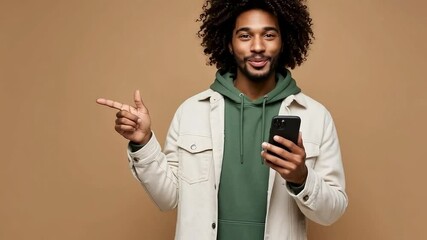 A happy man points to the side while holding his phone