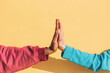 © Renata Hamuda - Close up of Unrecognizable multiracial people's hands giving high five to each other against yellow background