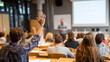 © tong2530 - Wide shot of university classroom with professor interacting with student raising hand, students listening, projector and educational material visible, professional and dynamic education scene