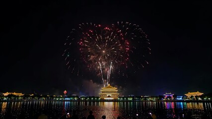 Wall Mural - fireworks light up the sky over a lake with a building in the background