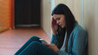 © Yuliia - Caucasian sad upset student girl female schoolgirl woman ill reading bad news thinking pupil teen in school university college sitting on floor education study problem using mobile phone smartphone