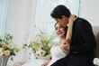 © supAVADEE BUTRADEE - Beautiful Asian bride in white dress. Handsome groom in black suit, wearing ring and kissing bride with love and happiness at wedding.