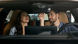 © Yuliia - Happy couple sitting inside new luxury modern electric car choosing automobile looking around married Caucasian man with woman choosing auto in salon discuss talking smiling rent service credit buying