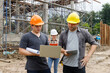 © skarie - Construction engineers using laptop and tablet to discuss project progress at building site. Team collaboration in civil engineering and site supervision concept.