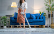 © PaeGAG - Housewife using cordless vacuum cleaner, cleaning carpet in living room at home