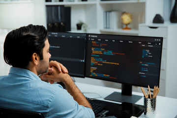 Concentrating in smart IT developer working software development coding on two pc screen, creating virus firmware application program for latest update version on website at modern office. Surmise.