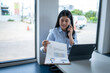 © Apichat - woman is talking on her cell phone while looking at a piece of paper