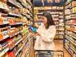 © Apichat - woman is shopping in a grocery store and is holding two blue containers