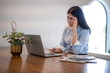 © Apichat - woman is sitting at a desk with a laptop and a potted plant