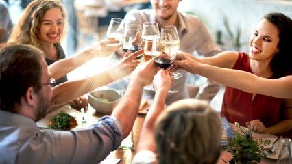Wall Mural - diverse group celebrating with wine at a festive gathering. people enjoying a meal, raising glasses,