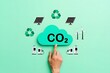 © Md Fazly Rabby - Reducing CO2 Emissions and Promoting Sustainability Concept. A hand holds green CO2 cloud icon with environmental symbols, such as solar, wind turbines, and recycling. Reduce carbon and go green.