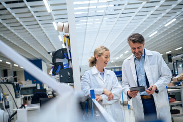 Happy businesswoman with colleague discussing over tablet computer