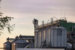 © Nastya_Photo - Large metallic silos store harvested grain, showcasing the industrial structure of a busy agricultural facility amid the harvest season.