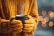 © whitestorm - Cozy winter morning: Hands in knitted gloves holding steaming mug, warm drink, blurry lights background. Comfort and relax at cold weather indoors, hot beverage for the soul.