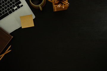 Wall Mural - dark workspace top view with laptop, notebook, pencils, and coffee cup