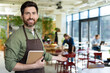 © zinkevych - Young bearded man in apron looking confident while waiting for the client in pizzeria