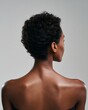 © rinrada - Back view of a Black woman showing subtle muscle tone and glowing skin. Captured under clean white light.