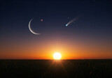 Sunrise over a grassy field with a crescent moon and comet in the evening sky. Peaceful landscape scene with celestial bodies for advertising/editorial use.
