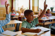 © Drazen - Black schoolboy raising hand to answer question in classroom.