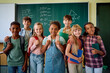 © Drazen - Multiracial group of happy schoolkids in classroom looking at camera.