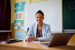 © Drazen - Happy black female teacher in classroom at elementary school looking at camera.