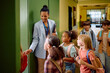 © Drazen - Happy black teacher welcoming her students on first day of school.