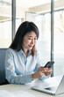 © Stock 4 You - Asian business woman manager ceo using cellphone mobile phone trade app. Smiling Korean female businesswoman holding smartphone in office for trading, working chat, looking at device screen. Vertical