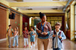 © Drazen - Happy black teacher and elementary student walking through hallway.