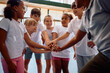 © Drazen - Happy kids and their coach joining hands in unity during PE class at school.