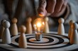 © koosy - A hand is lighting a light bulb centered on a bullseye, surrounded by multiple small wooden figures, used for corporate culture promotion, team collaboration, and leadership concepts.