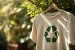 © TrubiAnna - A T-shirt made of recycled materials hangs on a wooden hanger. The shirt is light beige with a green recycling symbol, emphasizing sustainability and eco-friendliness.