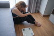 © Charlie's - Sad woman with fat upset bored of dieting Weight loss fail  Fat diet and scale sad asian woman on weight scale at home weight control