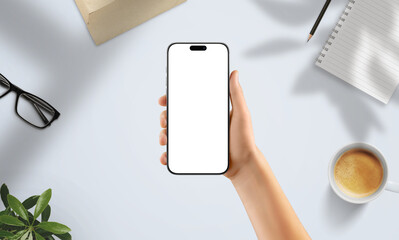Wall Mural - hand holding smartphone with blank screen in creative workspace. surrounded by coffee, notebook, gla