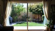 © somsri - Glass sliding doors with soft curtains framing view of private backyard