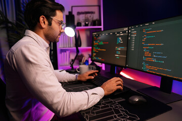 Working smart IT developer analyzing data software development on two pc screen, creating application program updated version online website page system online at neon light cyber office. Surmise.