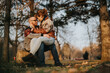 © qunica.com - A couple shares a tender moment seated together in a serene autumn park. The warm sunlight and golden leaves create a romantic and intimate atmosphere in this beautiful outdoor setting.