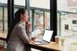 © jojo - Young woman working on laptop in coffee shop